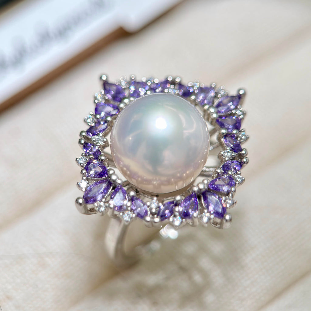 White freshwater pearl ring surrounded by purple sparkling stones.