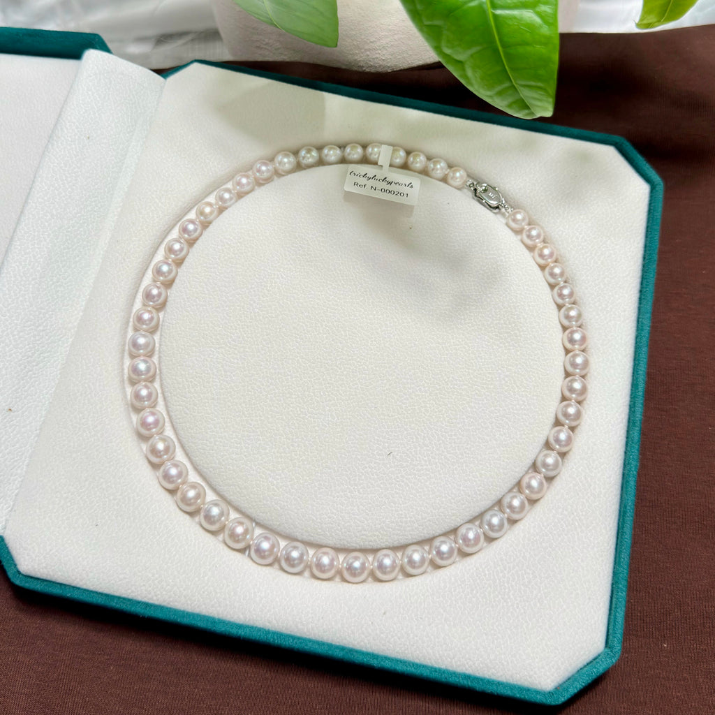 Close-up of 8–9 mm white freshwater pearls with soft pink halo.
