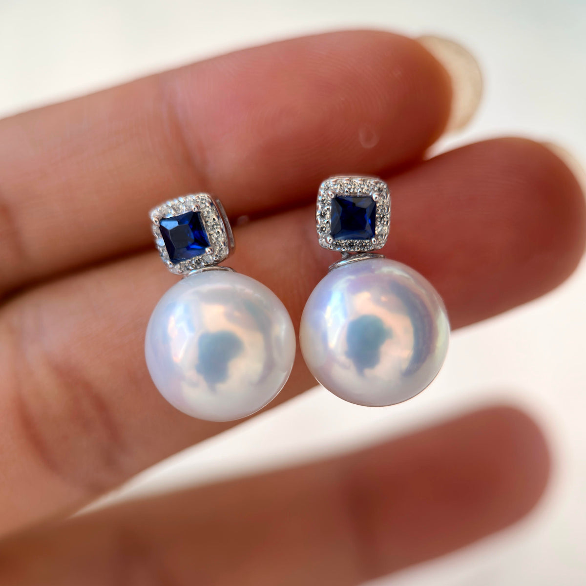 Large white pearl earrings with vivid cool blue overtones.