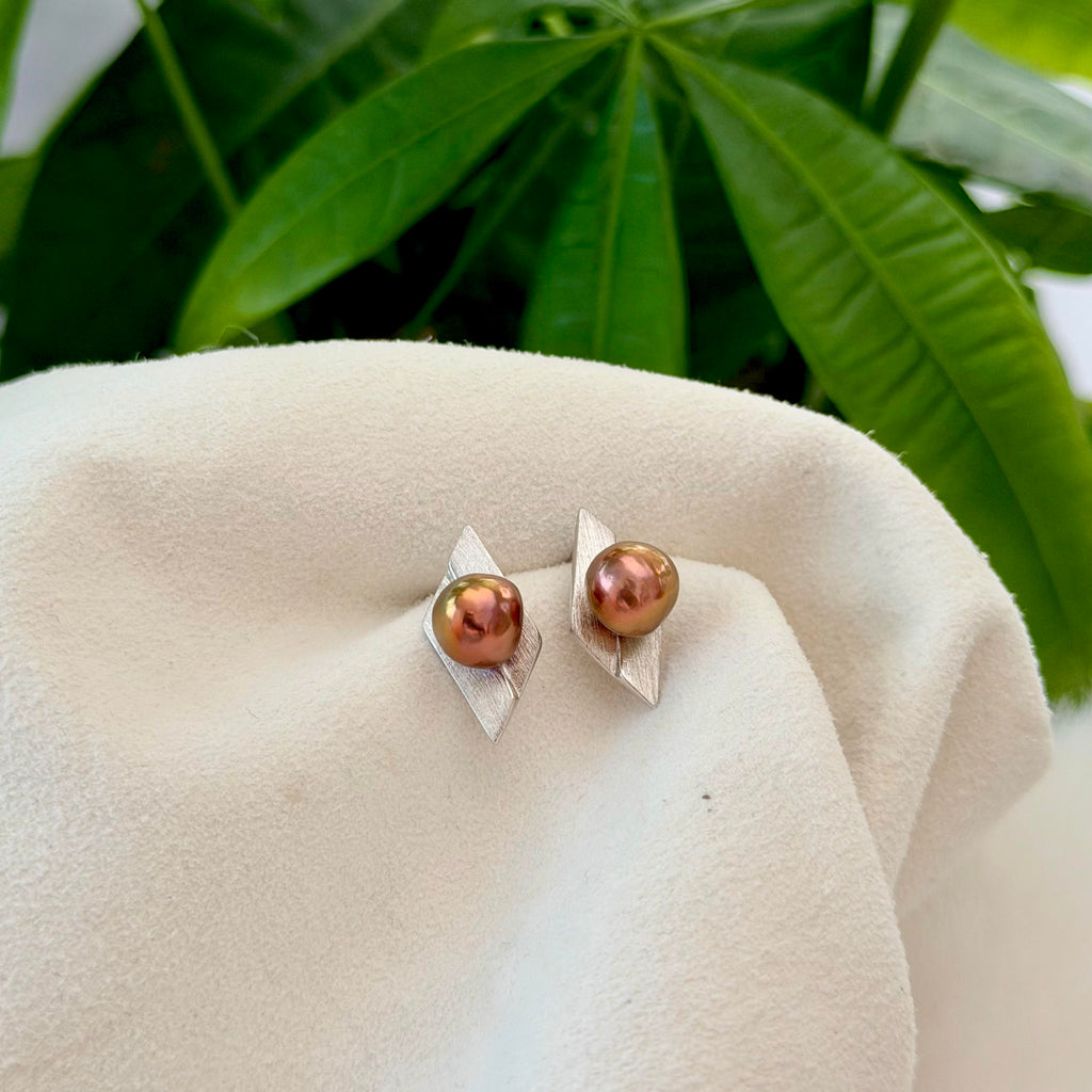 A pair of silver stud earrings with iridescent copper-brown pearls, Geometric pearl stud earrings presented as a refined gift for her.
