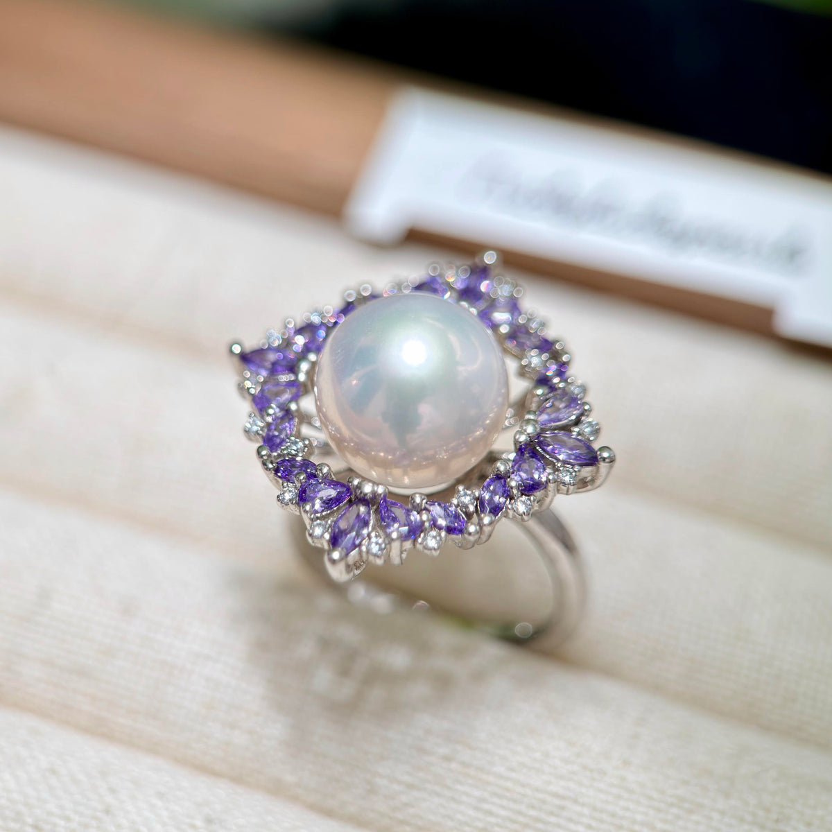 Adjustable sterling silver pearl ring with violet floral design.