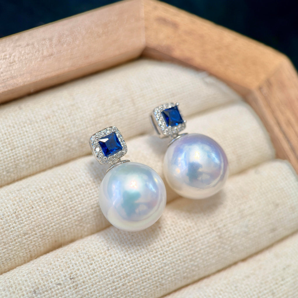 11.2 mm white freshwater pearl earrings with royal blue stone accents.
