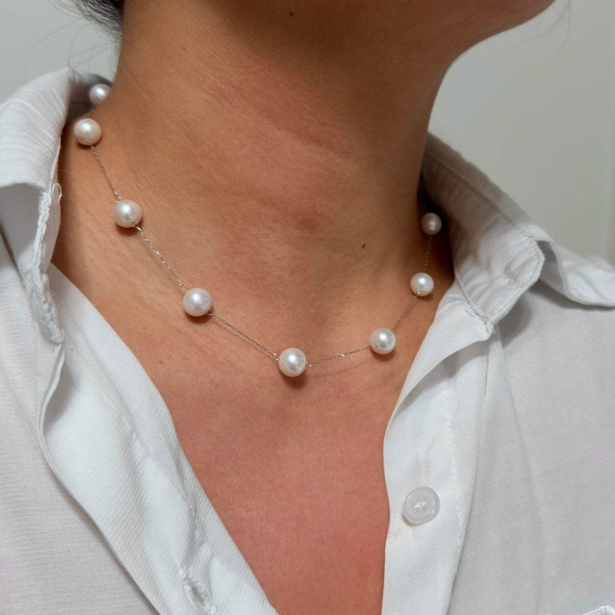 Minimalist white pearl necklace on a delicate silver chain.
