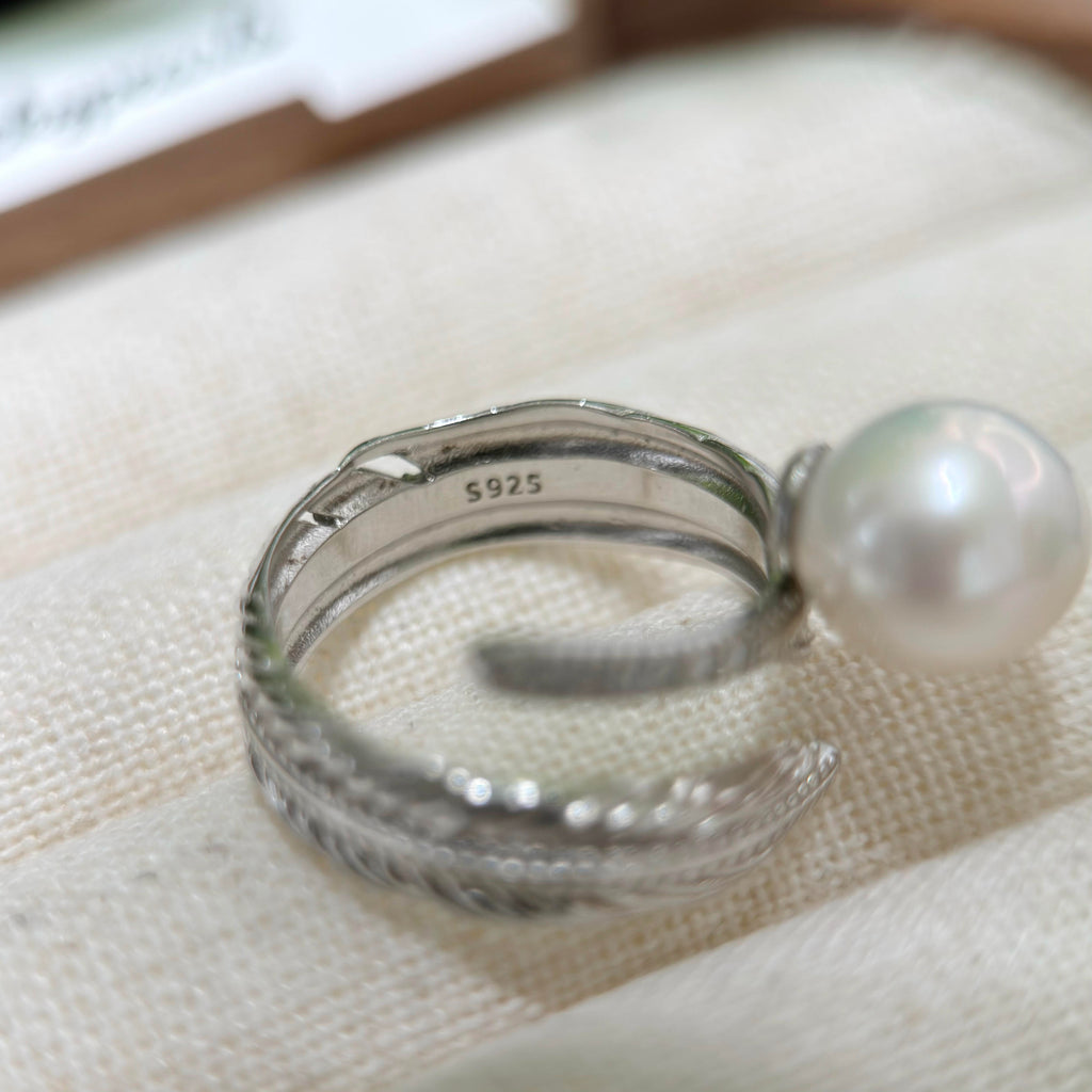 Close-up of finely sculpted silver feather pearl ring.