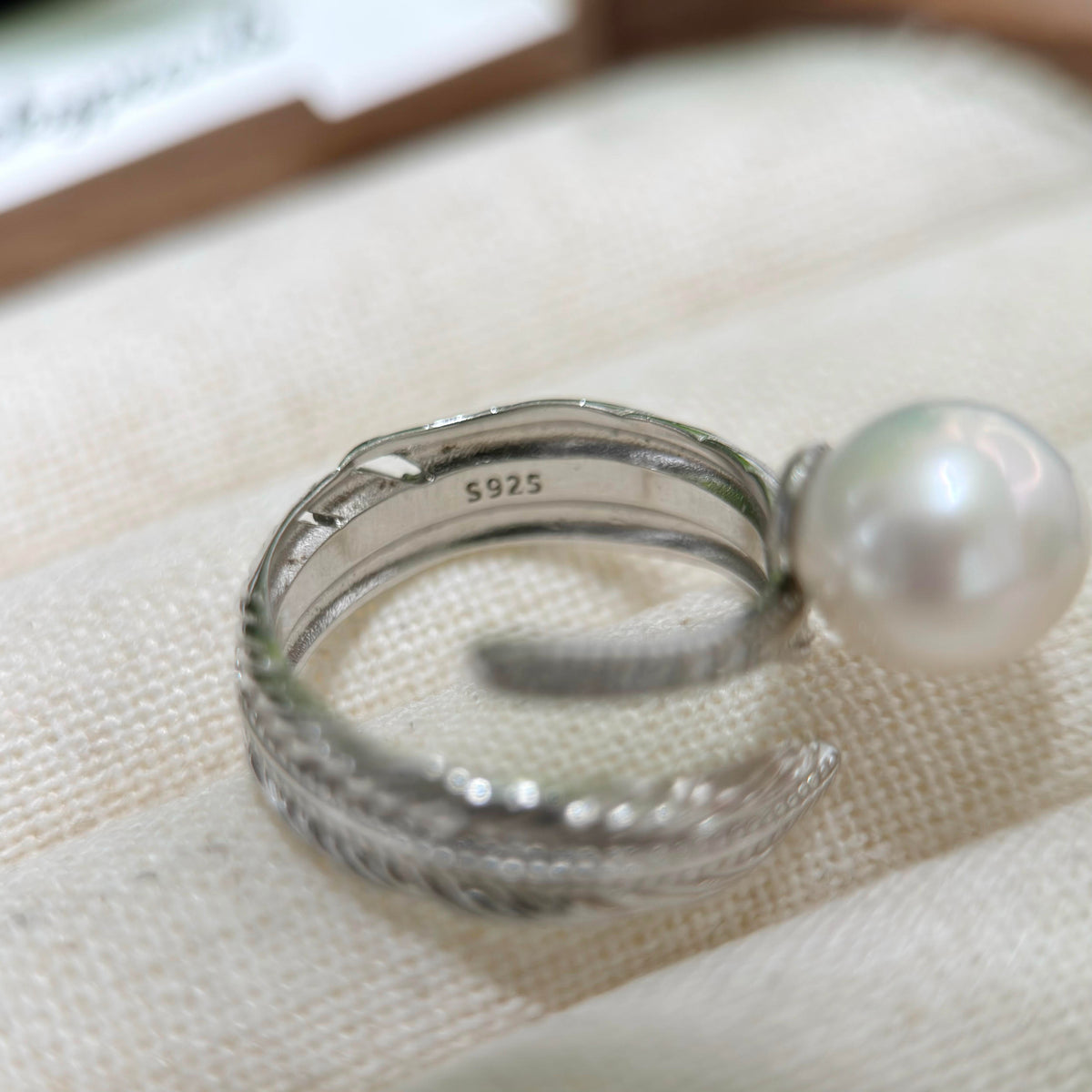 Close-up of finely sculpted silver feather pearl ring.