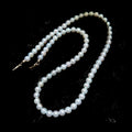 A strand of white freshwater pearls with a silver-toned clasp, displayed on a textured black background.