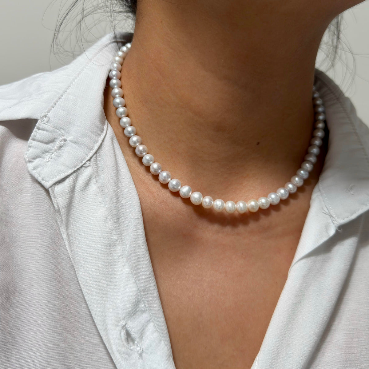 Minimalist natural pearl necklace designed to sit at the collarbone.