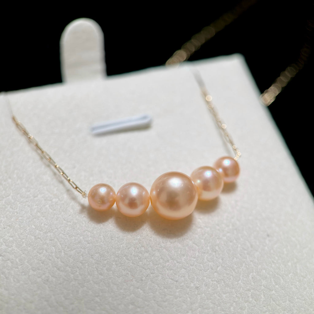 Smile-curve freshwater pearl necklace resting elegantly across the collarbone.