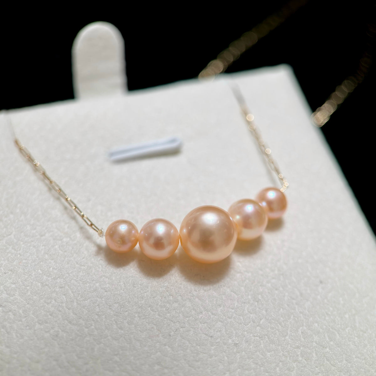 Smile-curve freshwater pearl necklace resting elegantly across the collarbone.