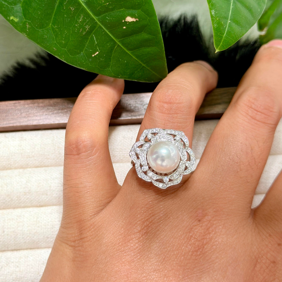 Garden-inspired camellia flower ring with sparkling stones and white pearl centre.