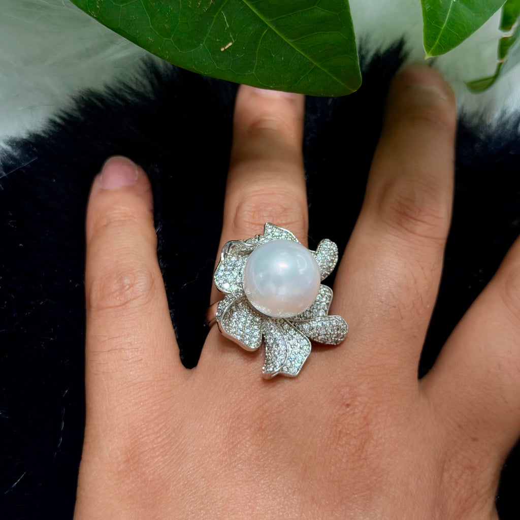 Large pearl ring with detailed multi-petal floral design.