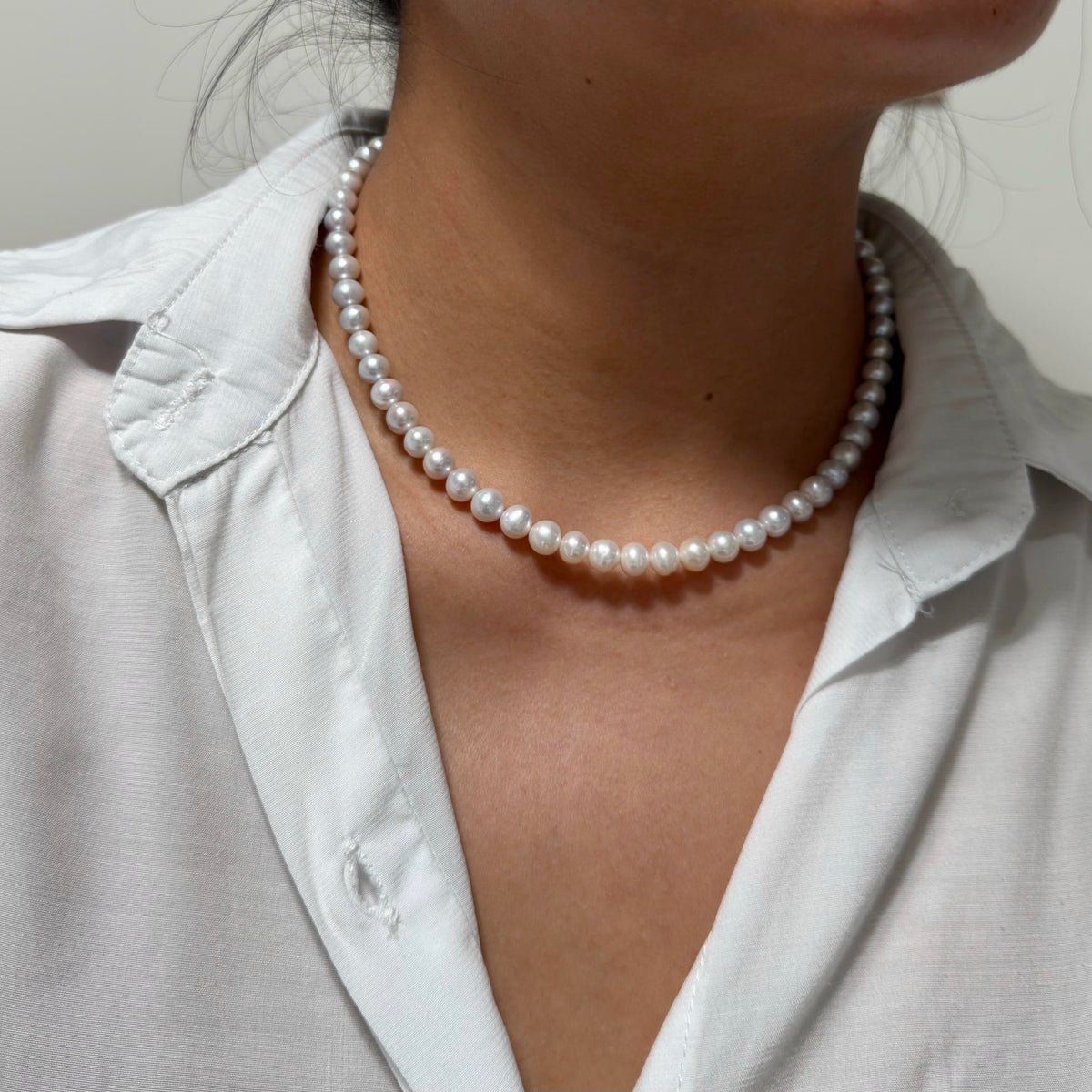 Grey and white freshwater pearl necklace displaying a soft blue halo.