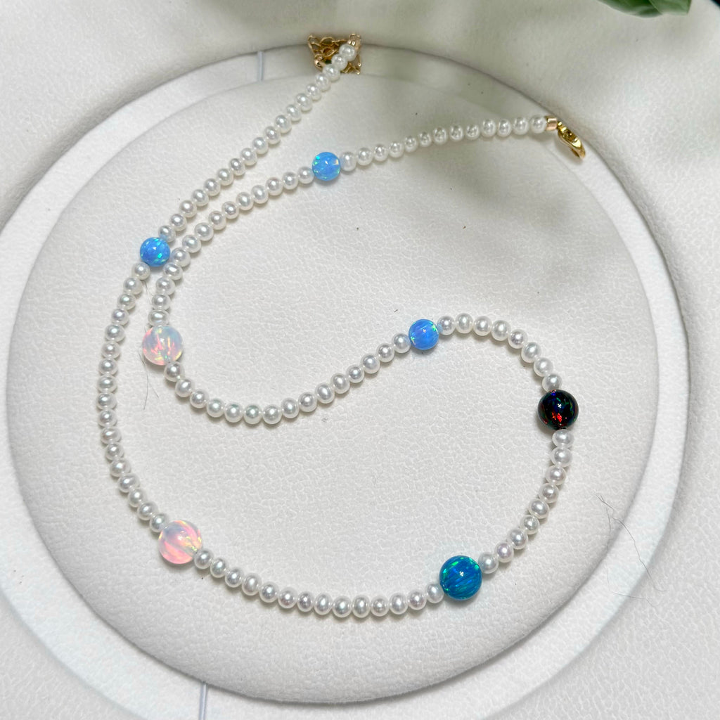 Celestial pearl necklace arranged with bright opal accents against a white background.