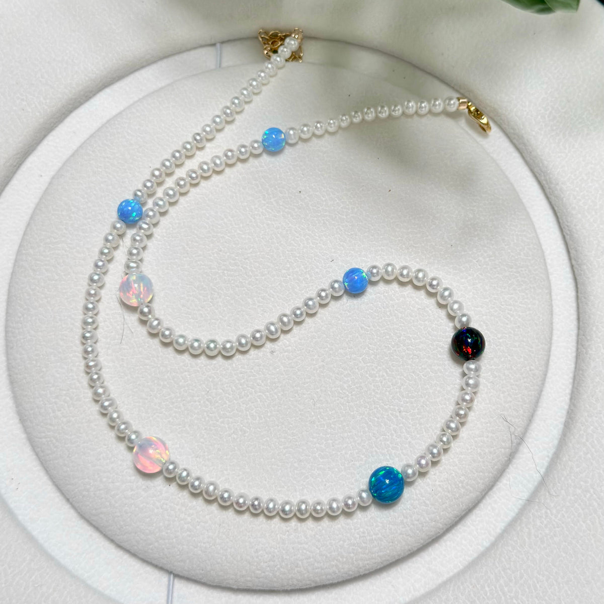 Celestial pearl necklace arranged with bright opal accents against a white background.