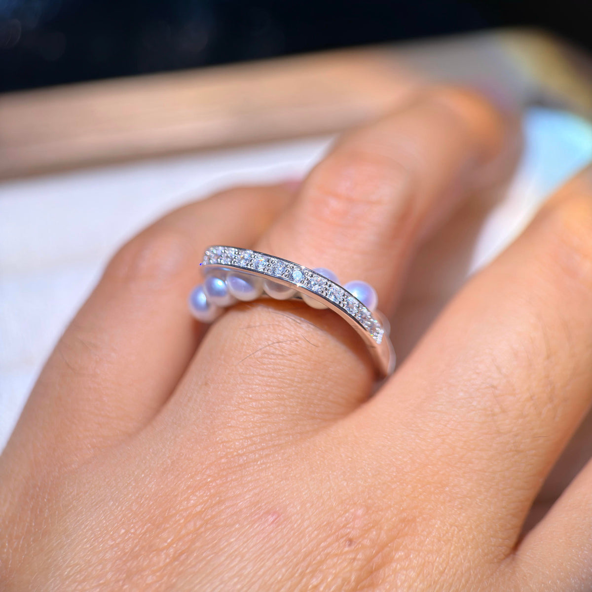 Sparkling open-band pearl ring with curved silver detail.