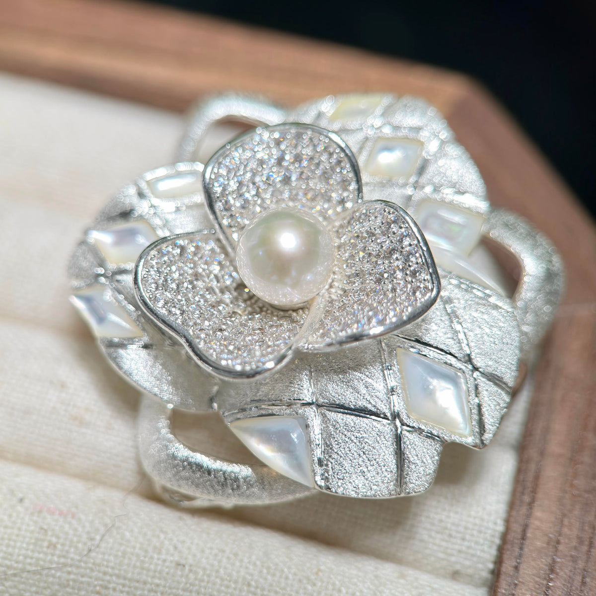 Camellia flower brooch featuring a luminous cool white freshwater pearl at the center.