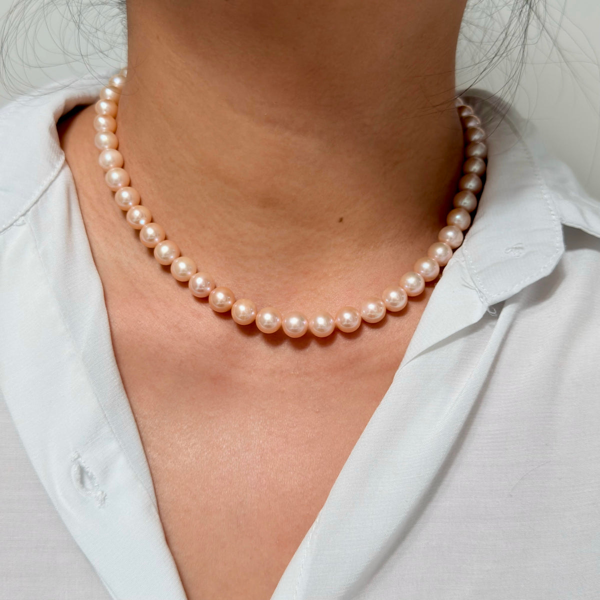 High-lustre freshwater pearl necklace in a warm light-orange shade on model.
