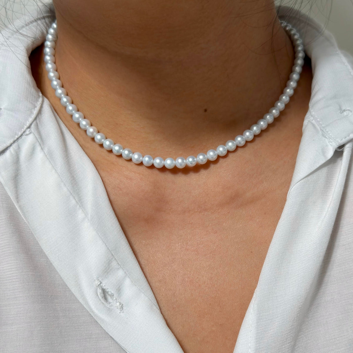 White freshwater pearl necklace displaying a cool blue overtone under light.
