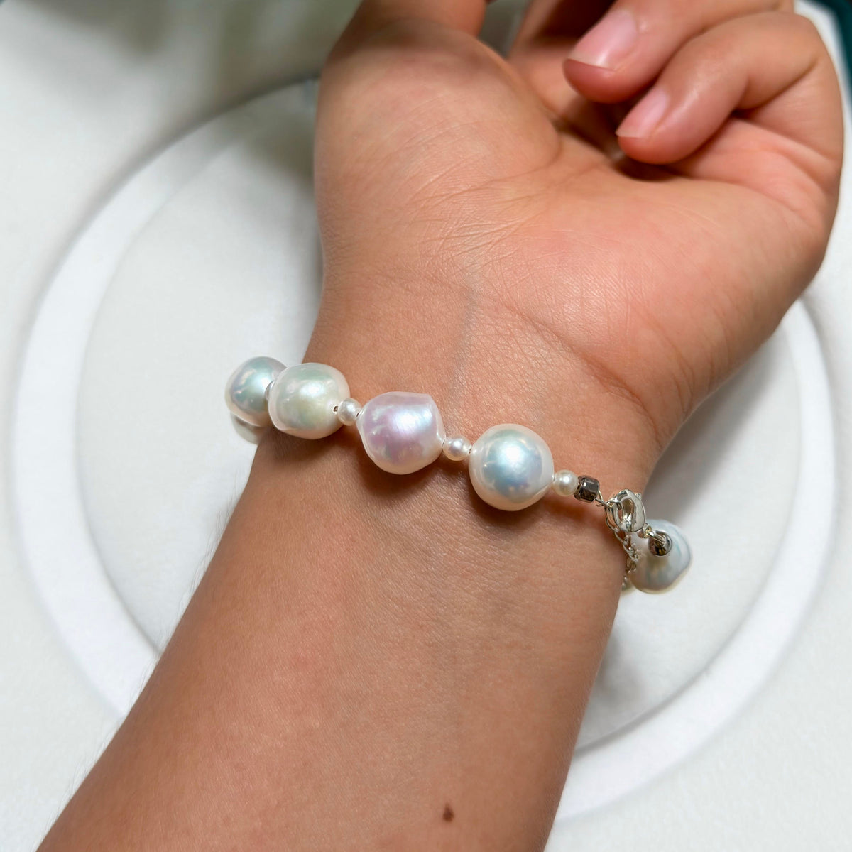 White ruffled baroque freshwater pearl bracelet with blue-pink iridescence and small pearl accents.
