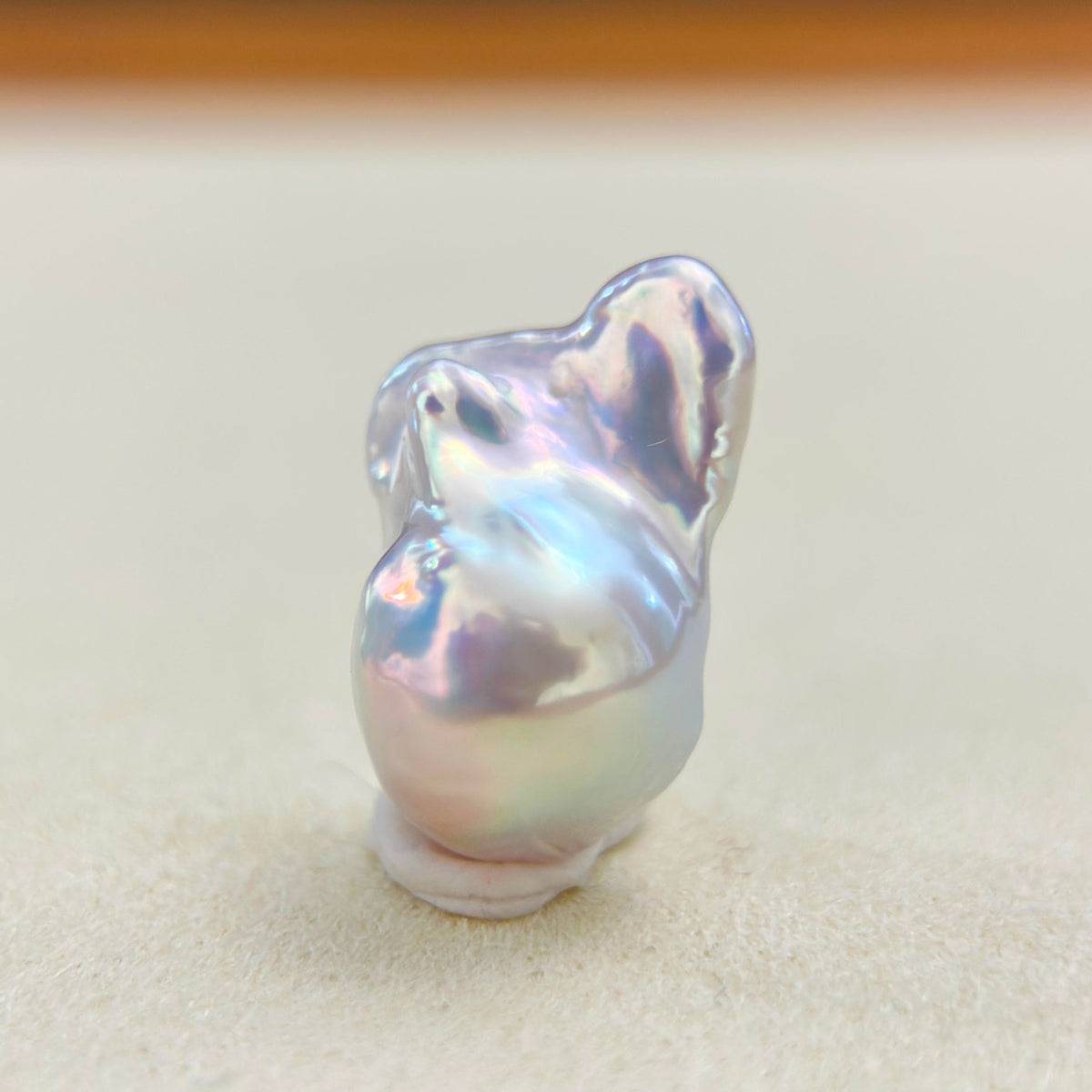 Mint green pearl pendant with blue iridescence and warm red halo accents.