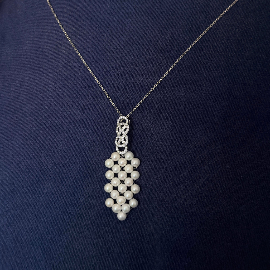 Woven freshwater pearl pendant necklace displayed against a dark background.
