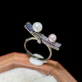 Movable seesaw pearl ring with white and purple-blue freshwater pearls.