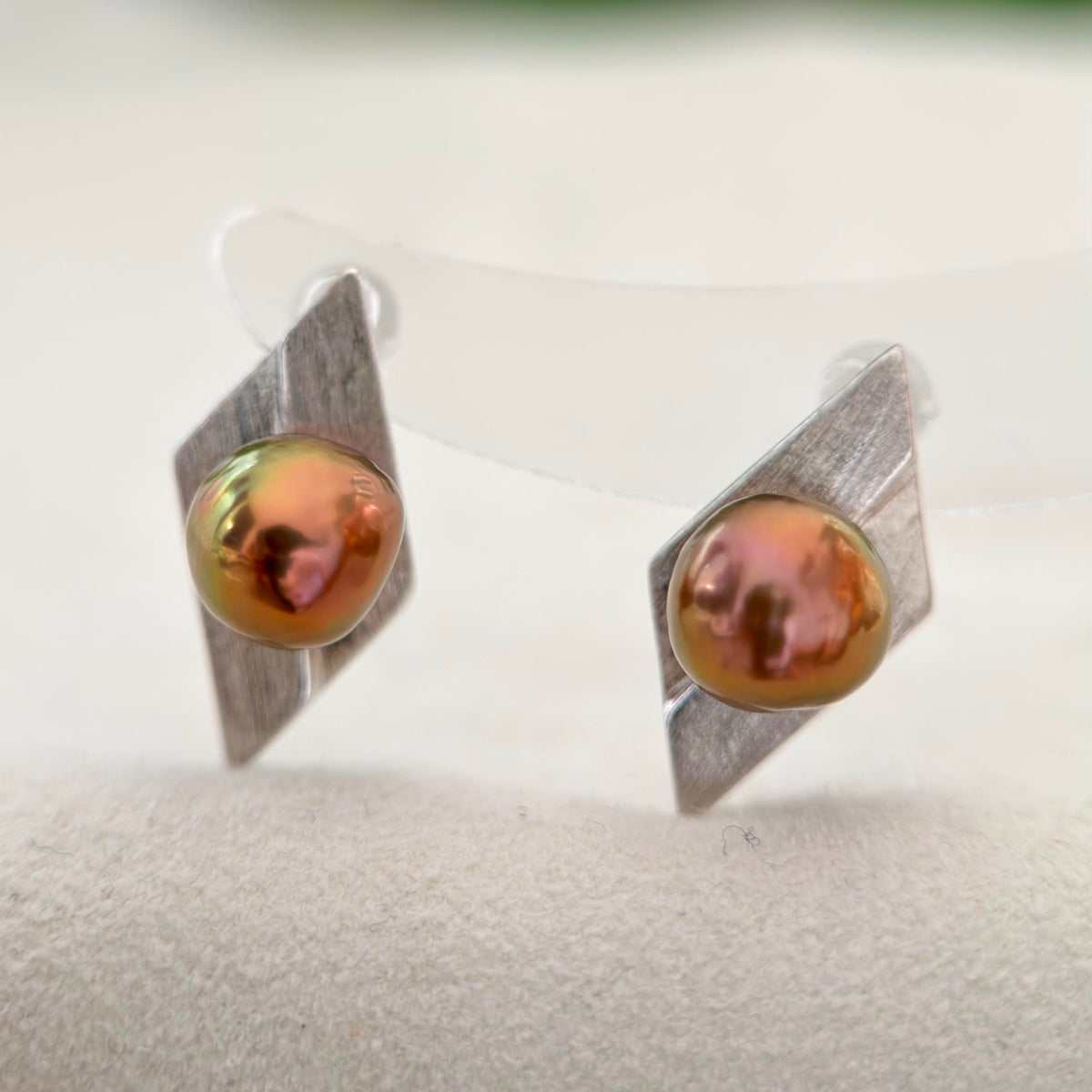 Brown and green-toned pearl earrings with a modernist jewelry aesthetic.
