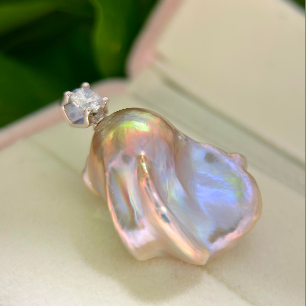 Statement jewelry design featuring whimsical blue baroque freshwater pearl pendant with colorful iridescent halo and silver setting.