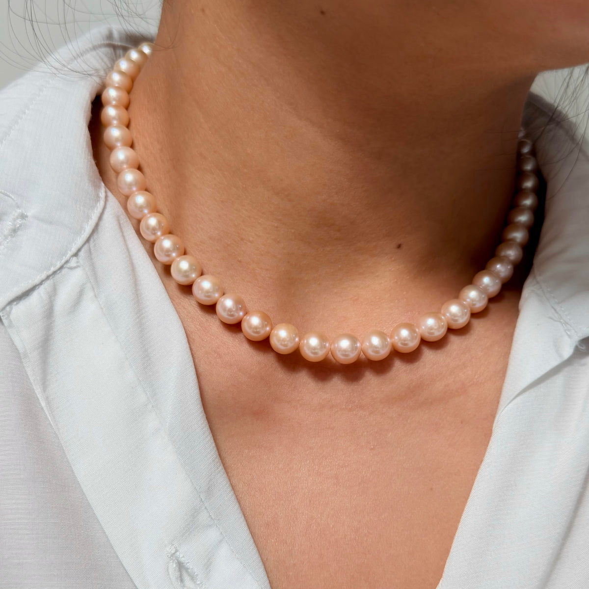 Warm-toned freshwater pearl necklace with subtle natural colour variation.
Classic orange pearl necklace styled at collarbone length.
