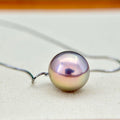 A single iridescent freshwater pearl pendant on a thin silver wire necklace, resting on a light beige textured surface.