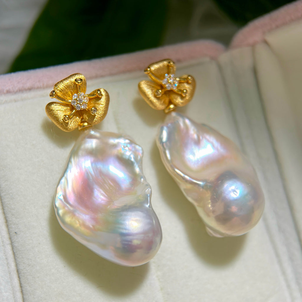 Pink and blue halo pearl earrings with textured floral studs.
