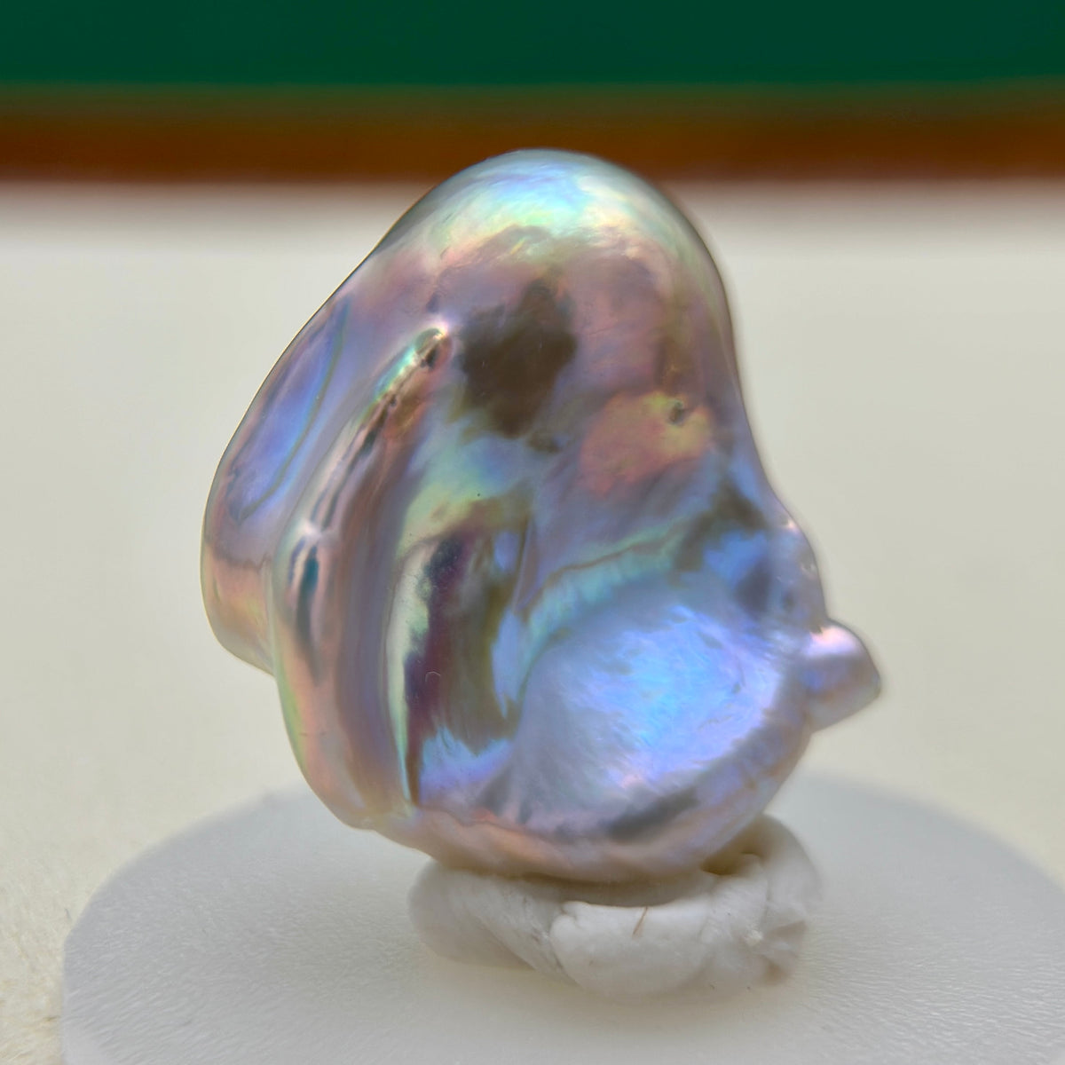 Natural pearl lustre shown on whimsical blue baroque freshwater pearl pendant with colorful iridescent halo and silver setting.