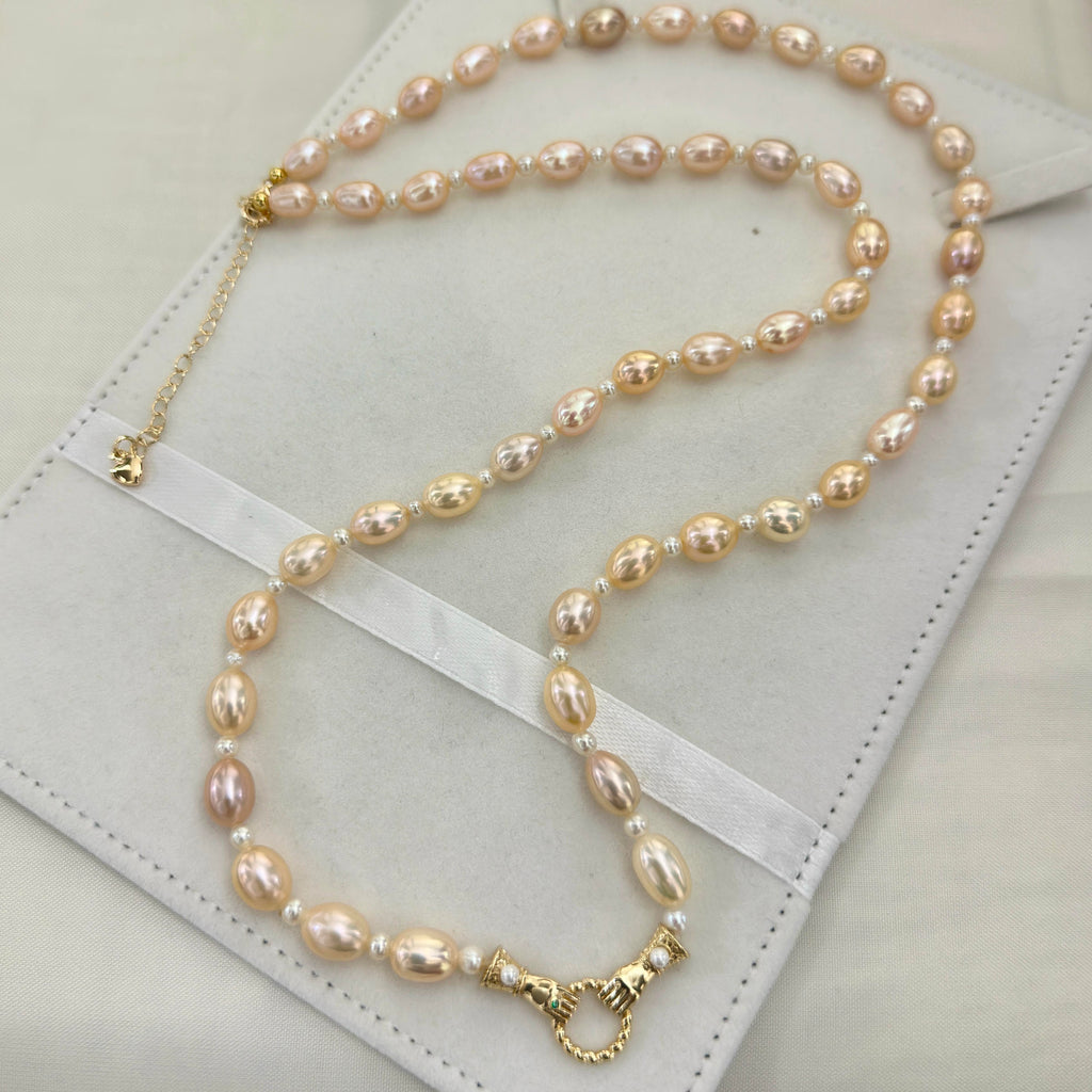 Elegant long freshwater pearl necklace with warm golden-orange oval pearls.