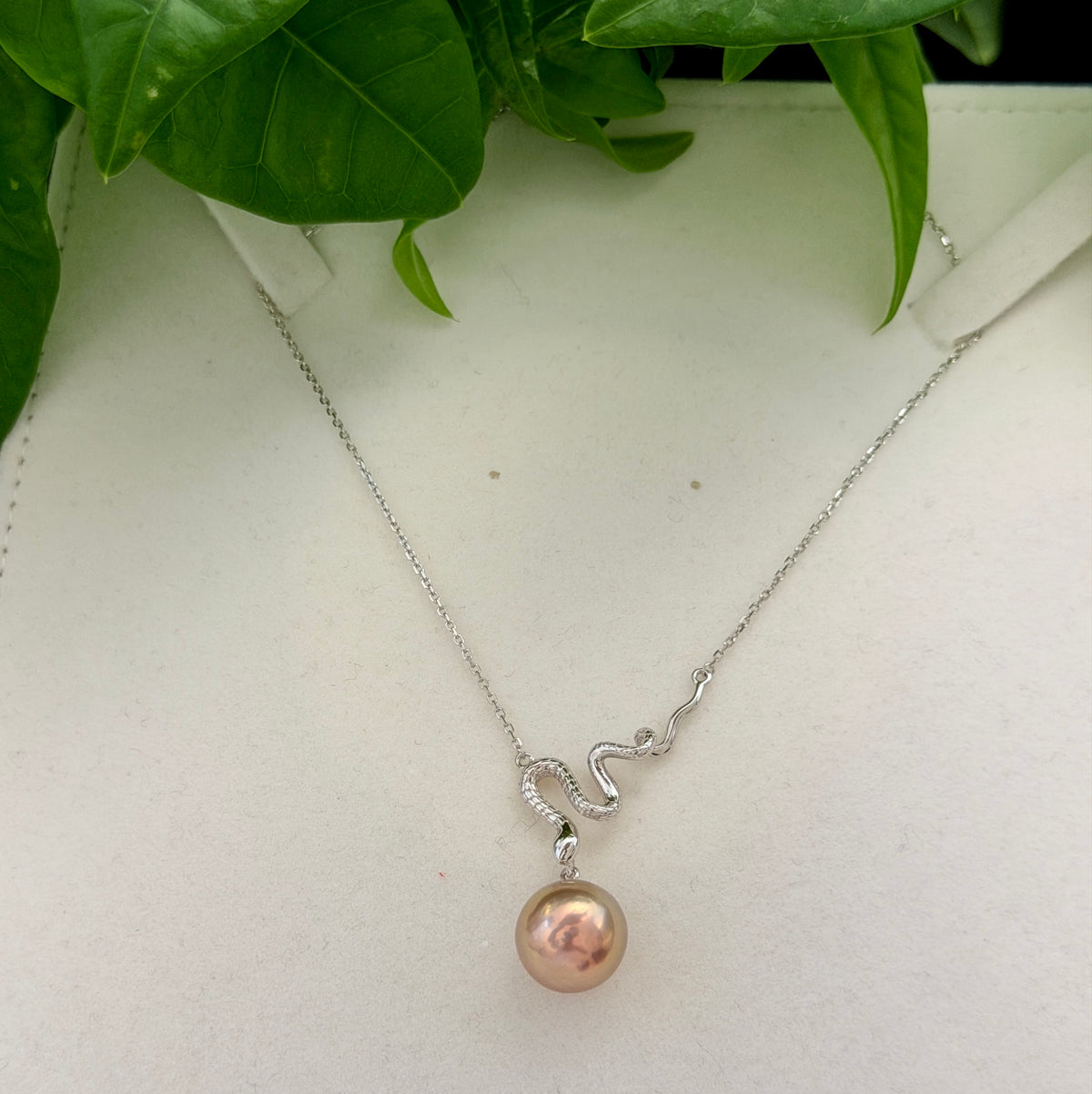 Close-up of a sculptural sterling silver snake and natural pearl pendant.