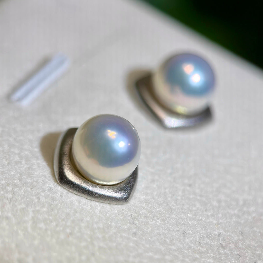 Mirror-luster pearl earrings displaying a cool blue halo.