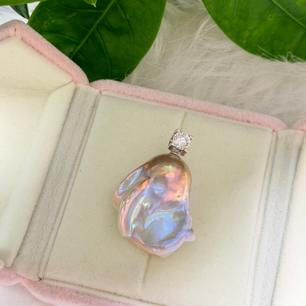 Organic pearl shape shown in whimsical blue baroque freshwater pearl pendant with colorful iridescent halo and silver setting.