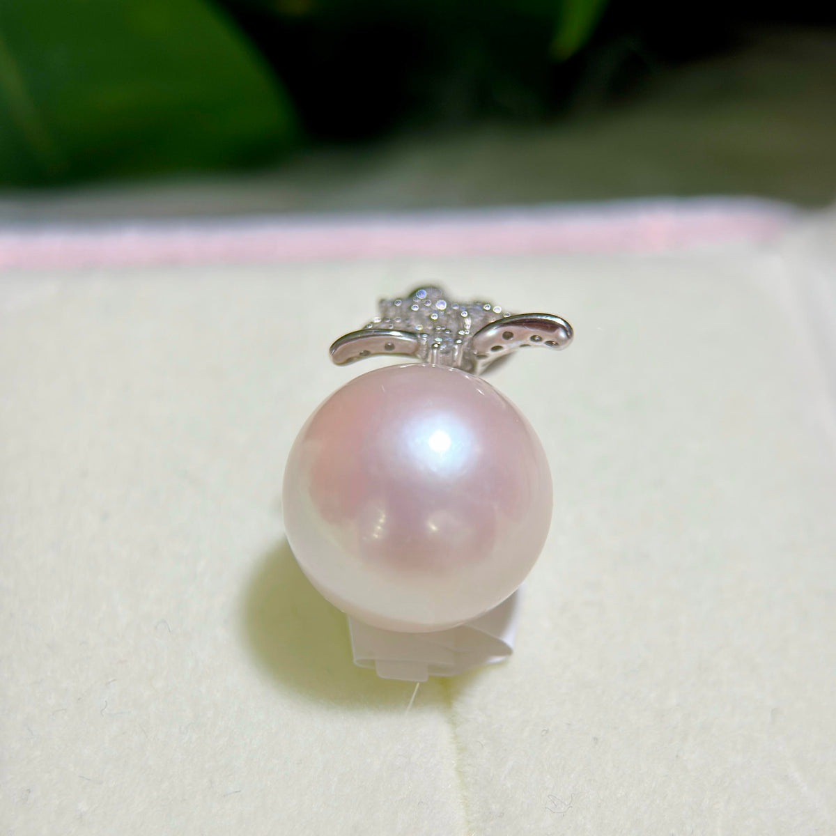 Close-up of a large white freshwater pearl with soft pink iridescence.