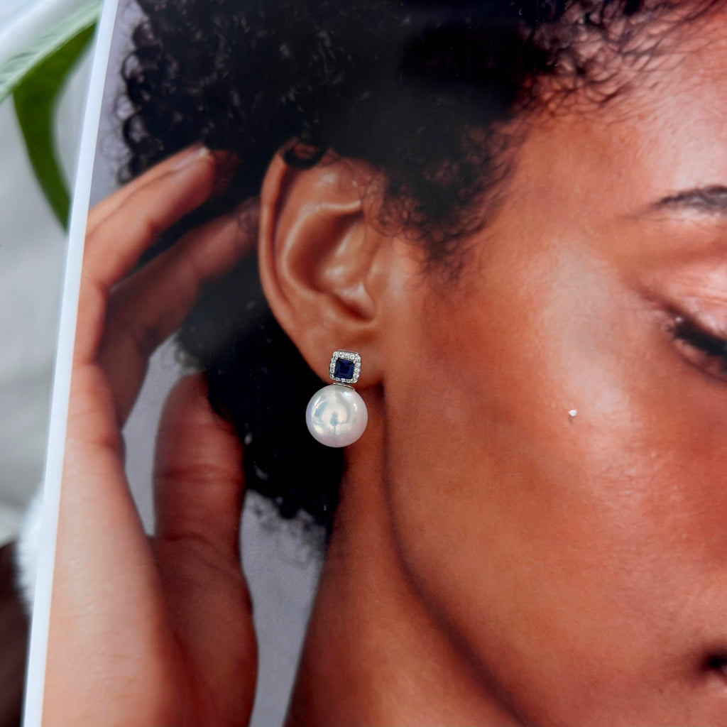 Luminous white pearl earrings styled as an elegant evening accessory.
