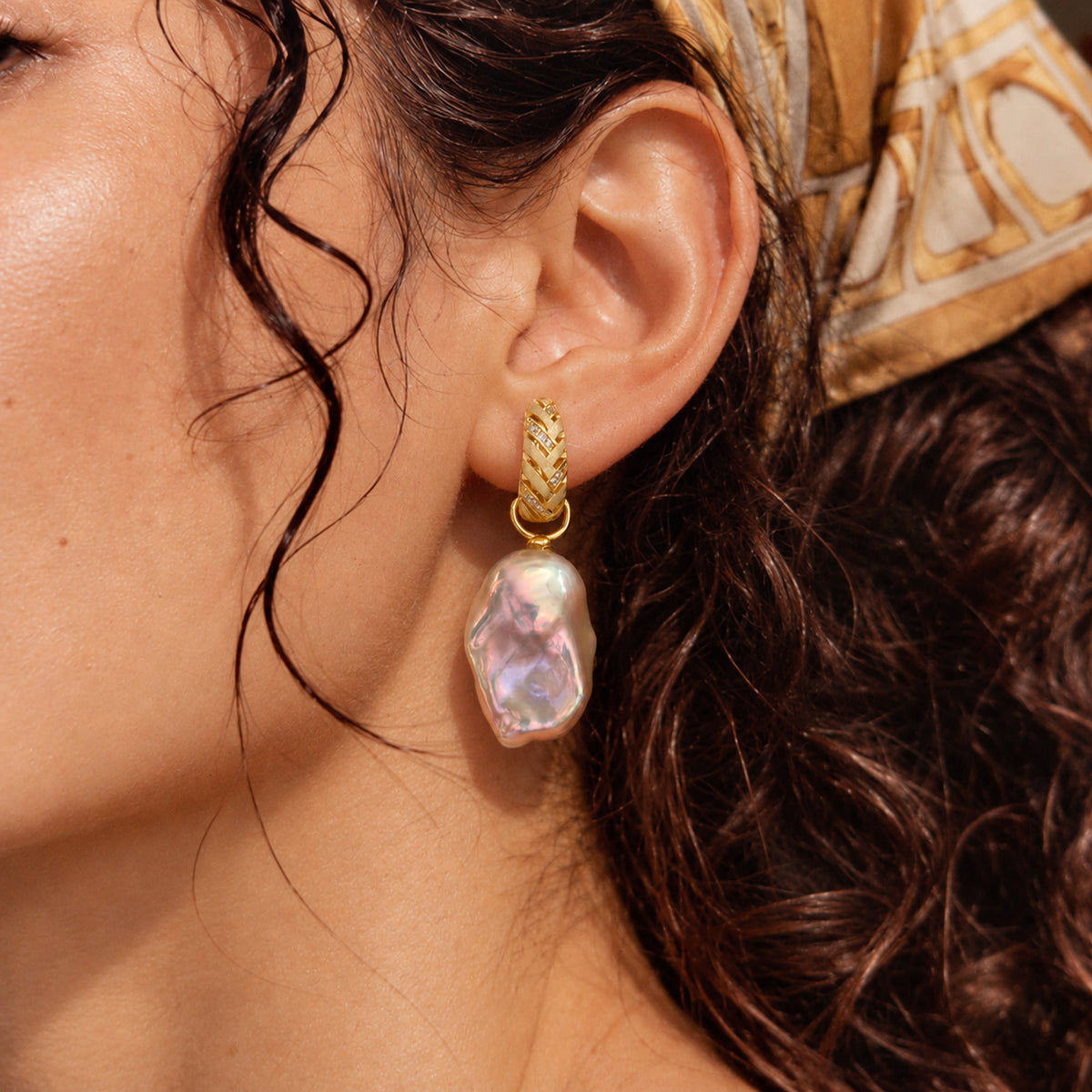 Model wearing golden-green pearl drop earrings.