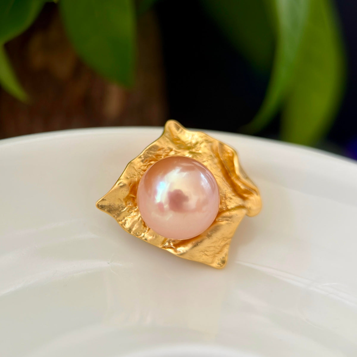 Textured silver setting surrounding a luminous golden freshwater pearl.