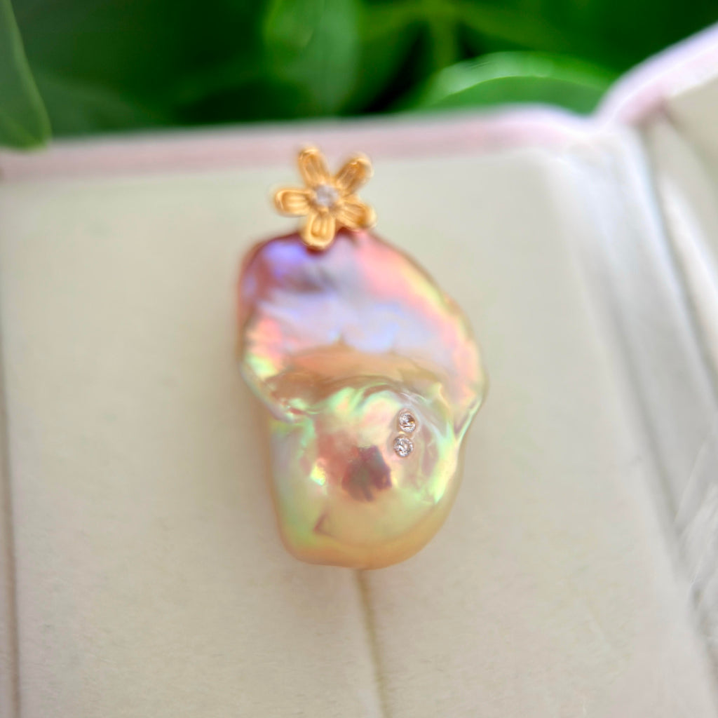 Detailed product view of golden-green baroque freshwater pearl pendant with sculptural osmanthus flower in sterling silver.
