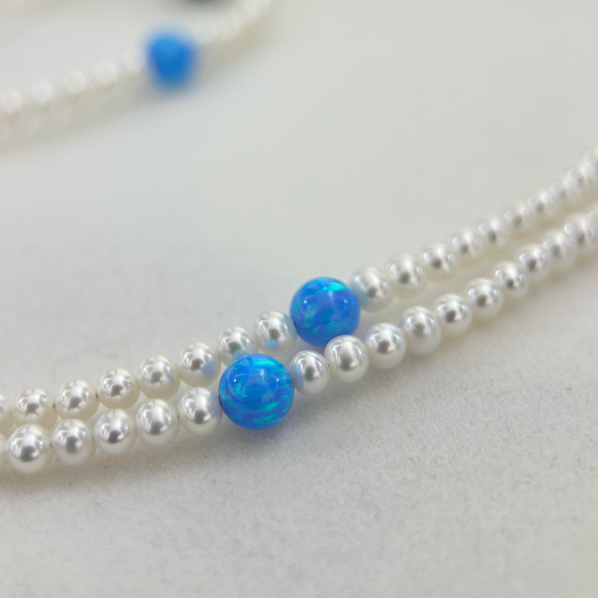 White freshwater pearl necklace accented with vivid blue opal beads.
