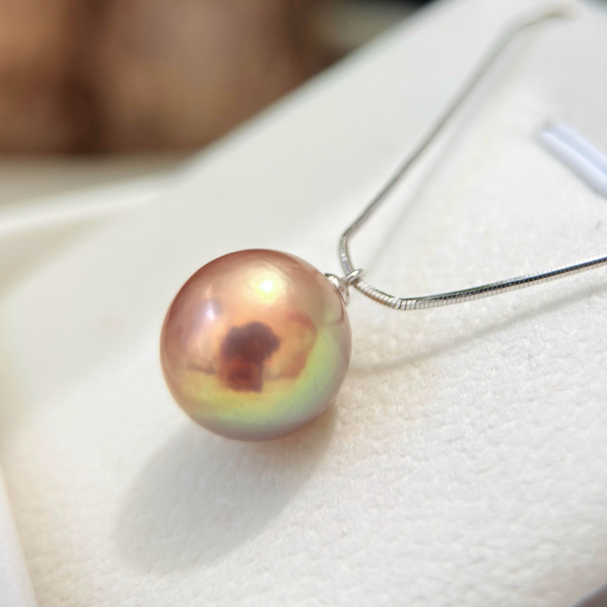 Natural pearl showing brown, golden, green and blue tones with a purple halo.