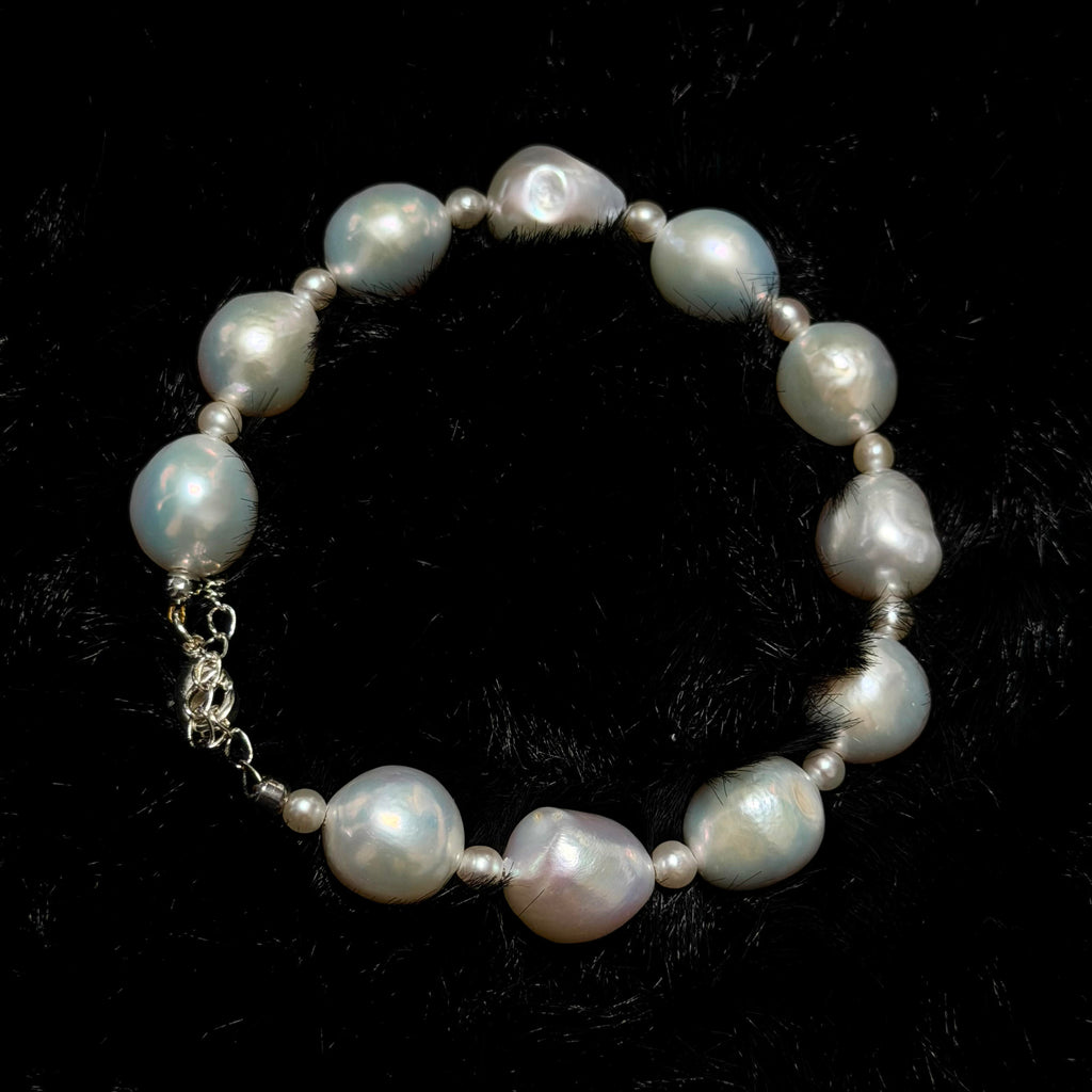 Freshwater pearl jewelry featuring white ruffled baroque pearl bracelet with blue-pink iridescence and small pearl accents.