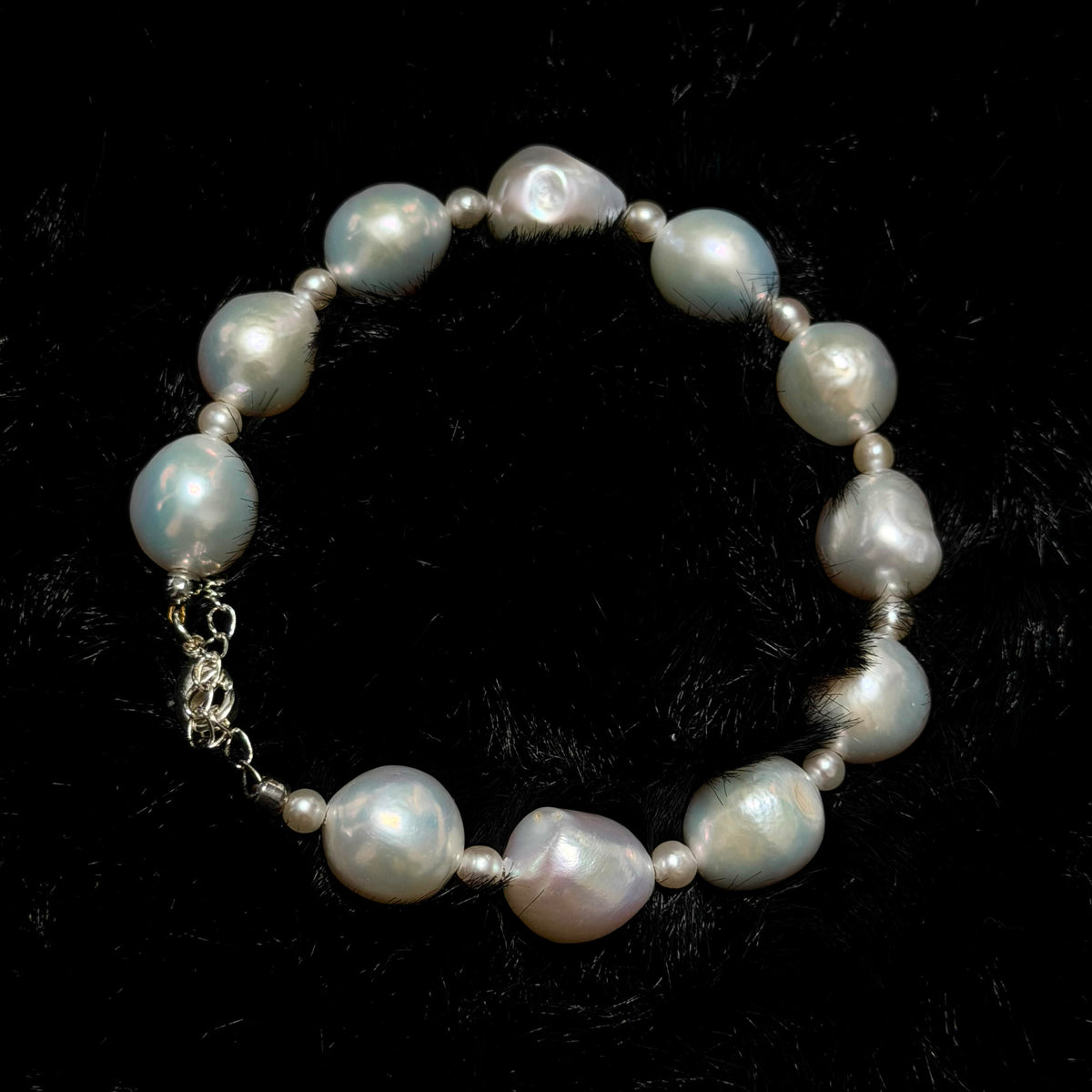 Freshwater pearl jewelry featuring white ruffled baroque pearl bracelet with blue-pink iridescence and small pearl accents.