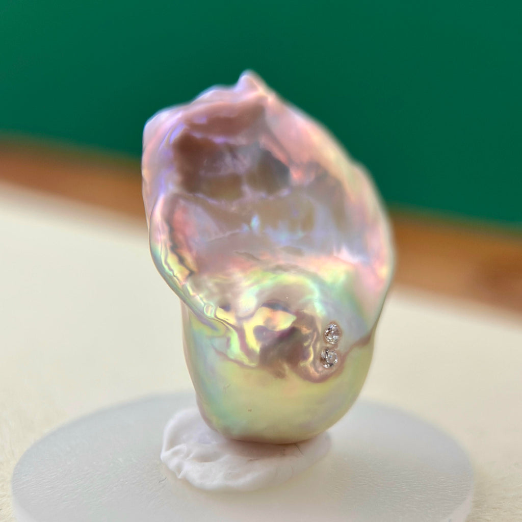 Close-up of golden-green baroque freshwater pearl pendant with sculptural osmanthus flower in sterling silver.