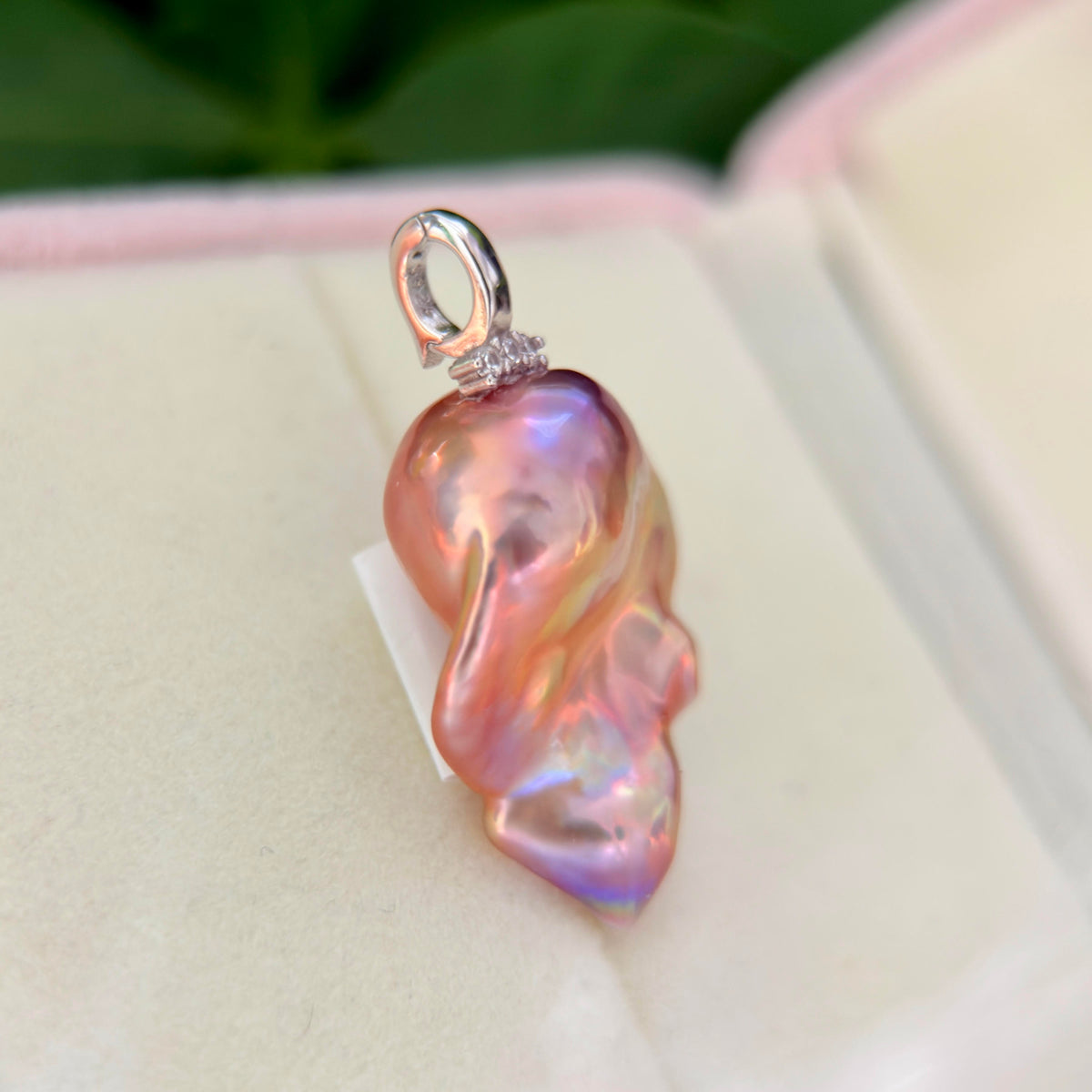 One-of-a-kind pearl pendant displaying an electric pink halo.
