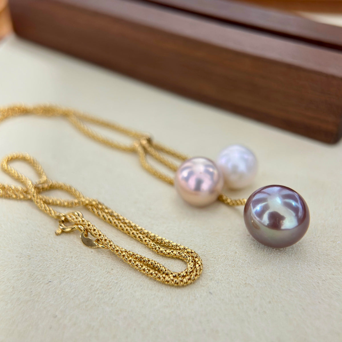 Colour-shifting freshwater pearls arranged in a modern necklace design.
Graduated three-pearl necklace creating an elegant collarbone silhouette.