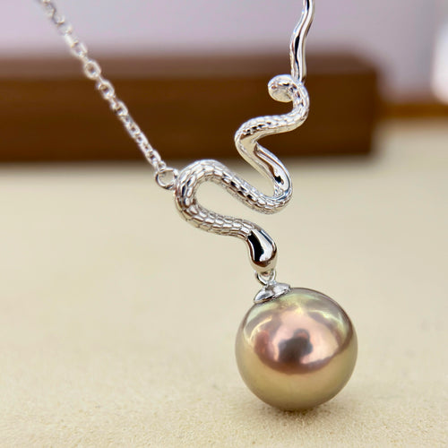 Sculptural silver snake pendant with a green, red and golden pearl.