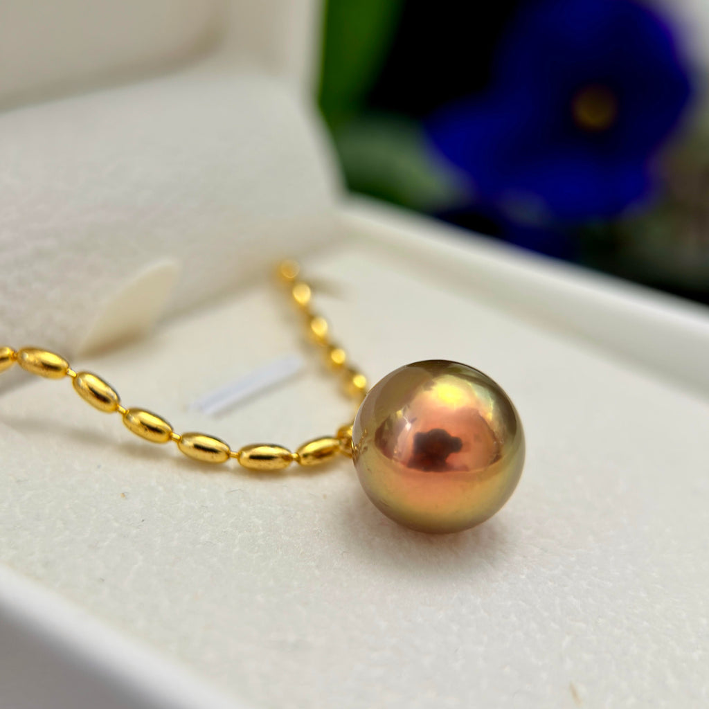 Natural pearl necklace showing deep green and golden colour with a faint purple halo.